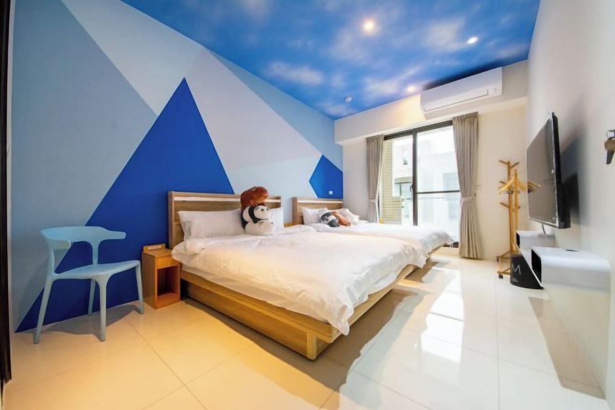 A modern bedroom with a large bed, a nightstand, a TV, and a window with curtains.