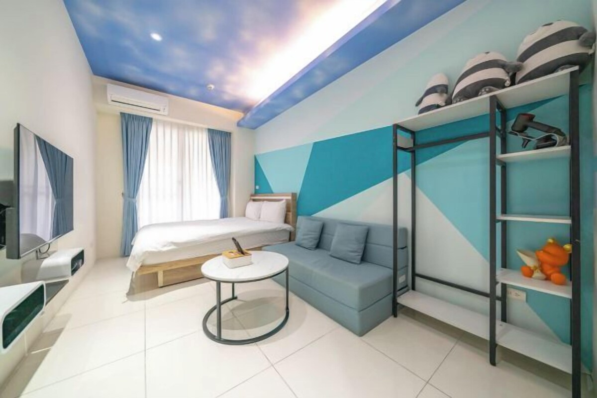 A modern hotel room with a bed, a sofa, a small round table, and a TV.