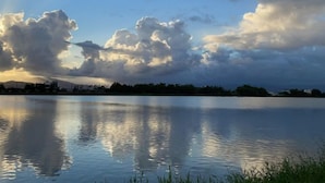 Un lago sereno con reflejos de nubes y el perfil distante de una ciudad.