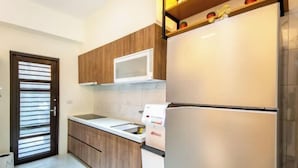 Una cocina moderna con armarios de madera, encimera blanca, microondas y refrigerador de dos puertas.