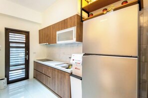 A kitchen with wooden cabinets, a microwave, a refrigerator, and a sink. - NEAR HOMESTAY (Yilan)