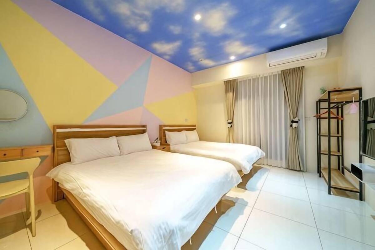 A hotel room with two beds, a ceiling mural, a TV, and a wardrobe.