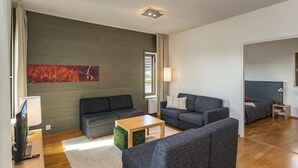 Una sala de estar moderna con un sofá gris, una mesa de centro de madera y un otoman verde.