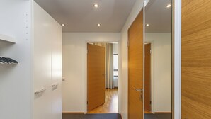 Un pasillo con una puerta de madera, una pared blanca y una alfombra gris.