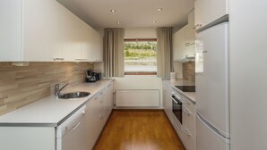 Una cocina moderna con gabinetes blancos, un fregadero de acero inoxidable y un horno empotrado.