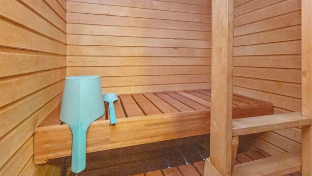 Un sauna avec des bancs en bois et un petit récipient bleu.