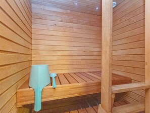 Una sauna con bancos de madera y un pequeño recipiente azul.