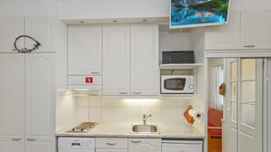 Une cuisine moderne avec des meubles blancs, un four à micro-ondes encastré, un lave-vaisselle et une grande fenêtre offrant une vue panoramique.