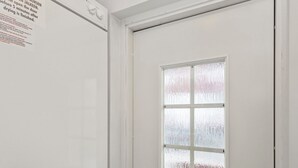 Une porte blanche avec un vitrage dépoli, une poignée de porte et un petit interrupteur carré.
