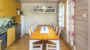 Eine kleine Küche mit Holzausstattung, einer Mikrowelle und einem Esstisch mit Stühlen.