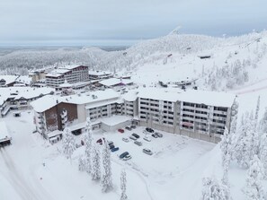 A snow-covered hotel with multiple buildings, a parking lot, and a ski lift in the background. - Ruka chalets 3202 by Interhome (Kuusamo)