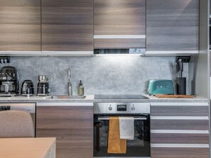 A modern kitchen with dark wood cabinets, a stainless steel sink, a coffee maker, a toaster, and an oven. - Ruka chalets 3202 by Interhome (Kuusamo)