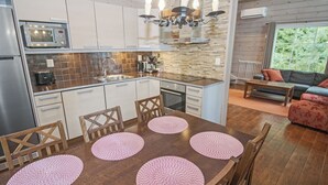 Eine moderne Küche mit Essbereich, ausgestattet mit einer zentralen Kochinsel, integrierten Geräten und einer Rückwand aus Stein.
