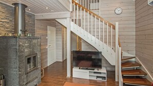 Ein modernes Wohnzimmer mit Kamin aus Stein, einer Wendeltreppe und einem Flachbildfernseher.