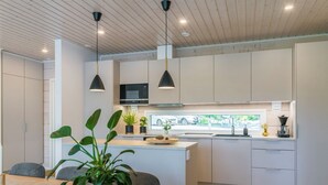 Una cocina moderna con una isla central, iluminación colgante y vistas a la calle.