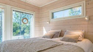 Un dormitorio acogedor con una cama grande, una ventana decorada con un adorno y paredes de madera.