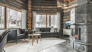 Ein gemütliches Blockhaus-Interieur mit Kamin aus Stein, einer Couch und einem Essbereich.
