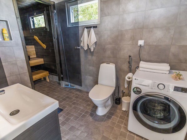 Un baño moderno con ducha, inodoro, lavadora y bañera.