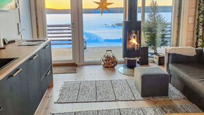 A cozy living room with a fireplace, a view of a snowy landscape, and a star decoration. - Niittyvilla by Interhome (Posio)