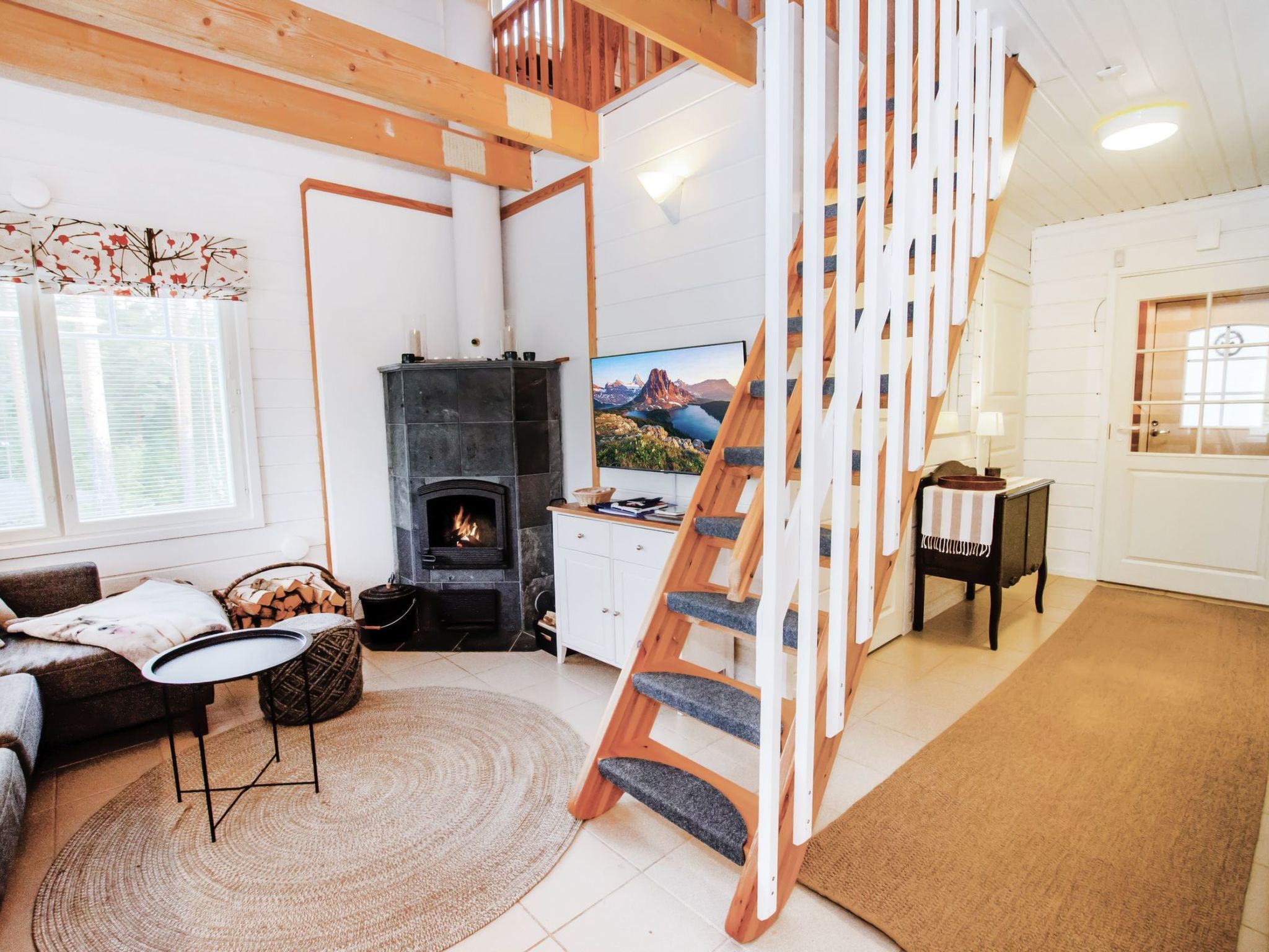 Un salon chaleureux avec une cheminée, un escalier en bois et un téléviseur.
