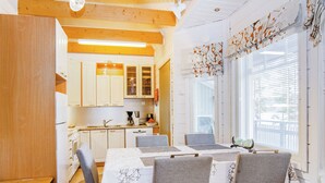 A modern kitchen with white cabinets, a dining table with grey chairs, and a window with blinds. - Saunaharju 6 by Interhome (Lieksa)