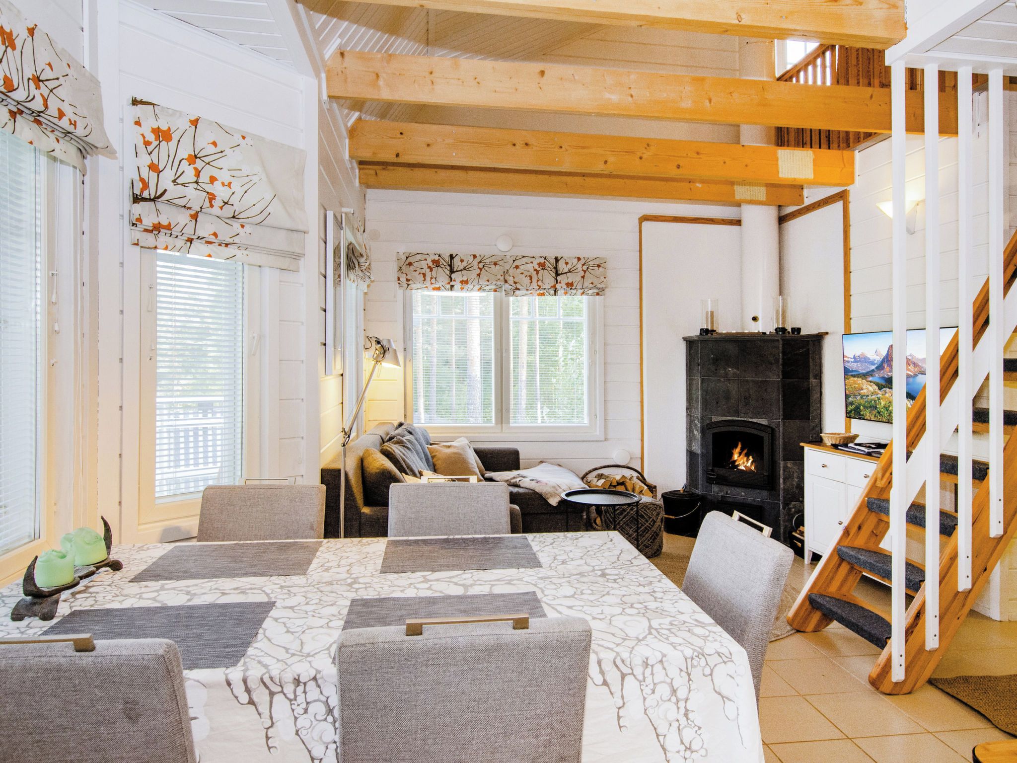Ein gemütliches Wohnzimmer mit Kamin, eine Essecke mit Tisch und Stühlen sowie eine Treppe, die in eine obere Ebene führt.