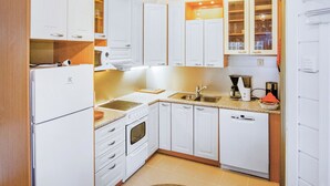 A compact kitchen with white cabinets, a built-in oven, a coffee maker, and a sink. - Saunaharju 6 by Interhome (Lieksa)