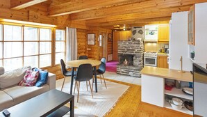 Un intérieur de chalet chaleureux comprenant un coin repas, une cuisine et une cheminée.