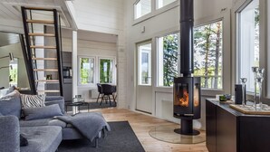 Un salon moderne avec une cheminée, un canapé, une table basse et un coin repas avec une chaise.
