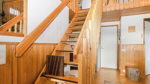 Eine Holztreppe mit Blick auf einen Raum, der eine Tür und eine Wanduhr zeigt.