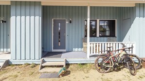 Ein hellblaues Holzhaus mit Veranda, einer Tür und einem Fenster.