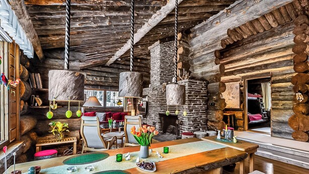 L’intérieur d’un chalet rustique, avec une cheminée en pierre, des meubles en bois et une grande table à manger.
