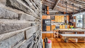 Une cuisine rustique avec des murs en pierre, des armoires en bois et une grande table en bois.