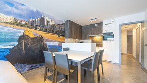 Een moderne keuken met een eethoek, met een groot muurschildering van een kuststadsgezicht.