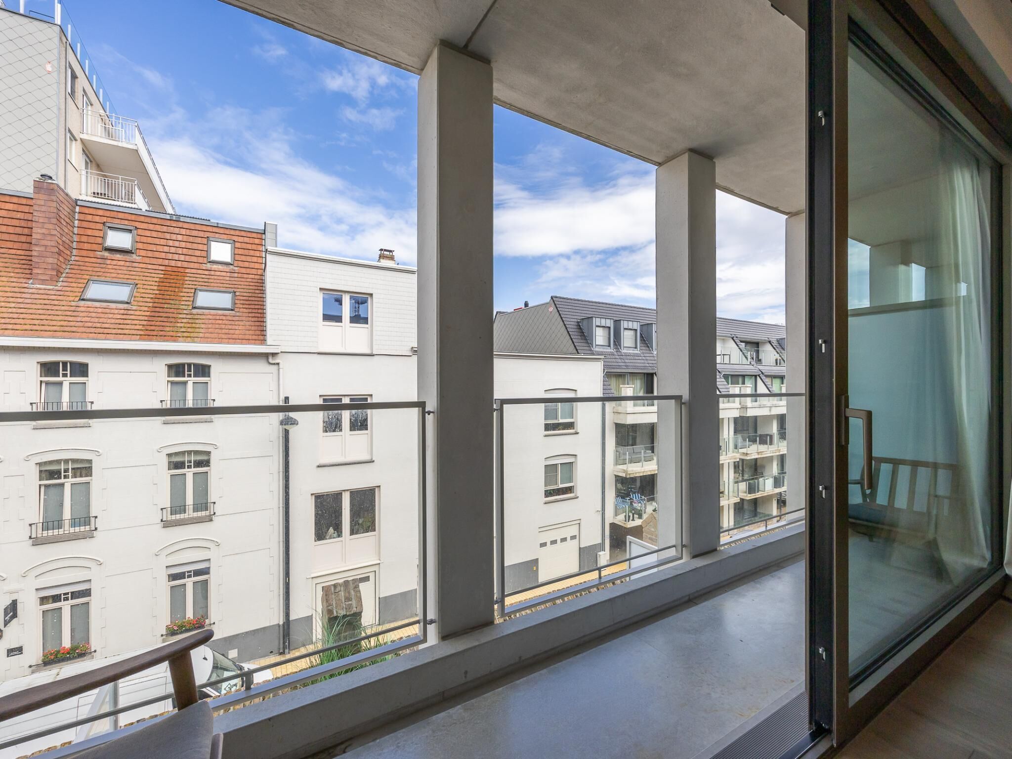 A balcony with a clear view of adjacent buildings, including a mix of residential and commercial structures. - Modern, bright studio near the sea (Middelkerke)