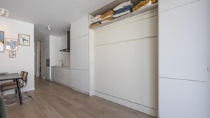 Una cocina moderna con armarios blancos, un comedor con mesa y sillas, y un pasillo que conduce a otra habitación.