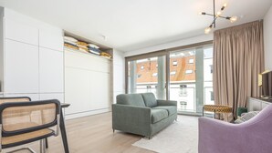 Una sala de estar moderna con un sofá, una silla, un televisor y un ventanal con cortinas.