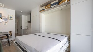 Un dormitorio moderno con cama, armario empotrado y kitchenette.