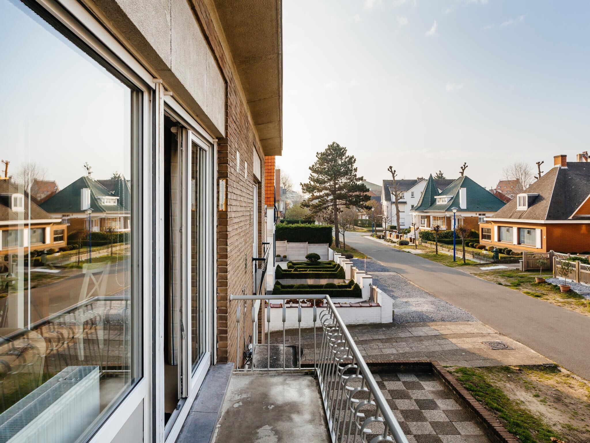A residential street with houses, a clear sky, and a visible road.