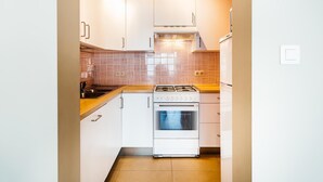 A compact kitchen with white cabinets, a gas stove, and a tiled backsplash. - Cosy flat near the centre (Koksijde)