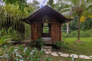 A wooden structure with a porch, surrounded by lush greenery and a stone pathway. - Casa Maroc Jungle Escape with Yoga Shala in Montezuma |Tropical Garden. (Montezuma)