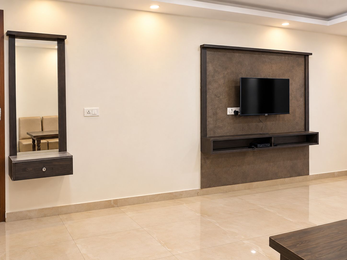 A modern living room with a flat-screen TV mounted on a wall, a built-in bench below, and a large mirror on the left.