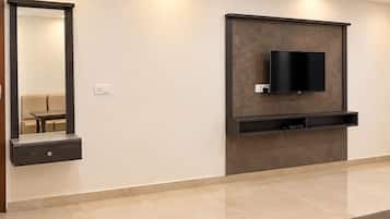 A modern living room with a flat-screen TV mounted on a wall, a built-in bench below, and a large mirror on the left.
