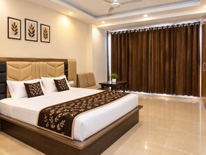 A hotel room with a large bed, a headboard, a bedside table with a plant, and a view of the outside through curtains.