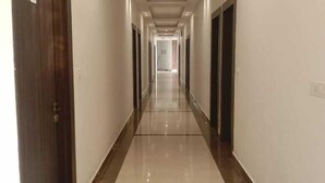 A long, narrow hallway with a tiled floor and doors on both sides.