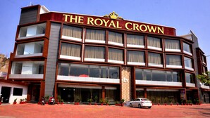 A multi-story hotel named 'The Royal Crown' with a prominent crown logo, large windows, and a red brick facade.