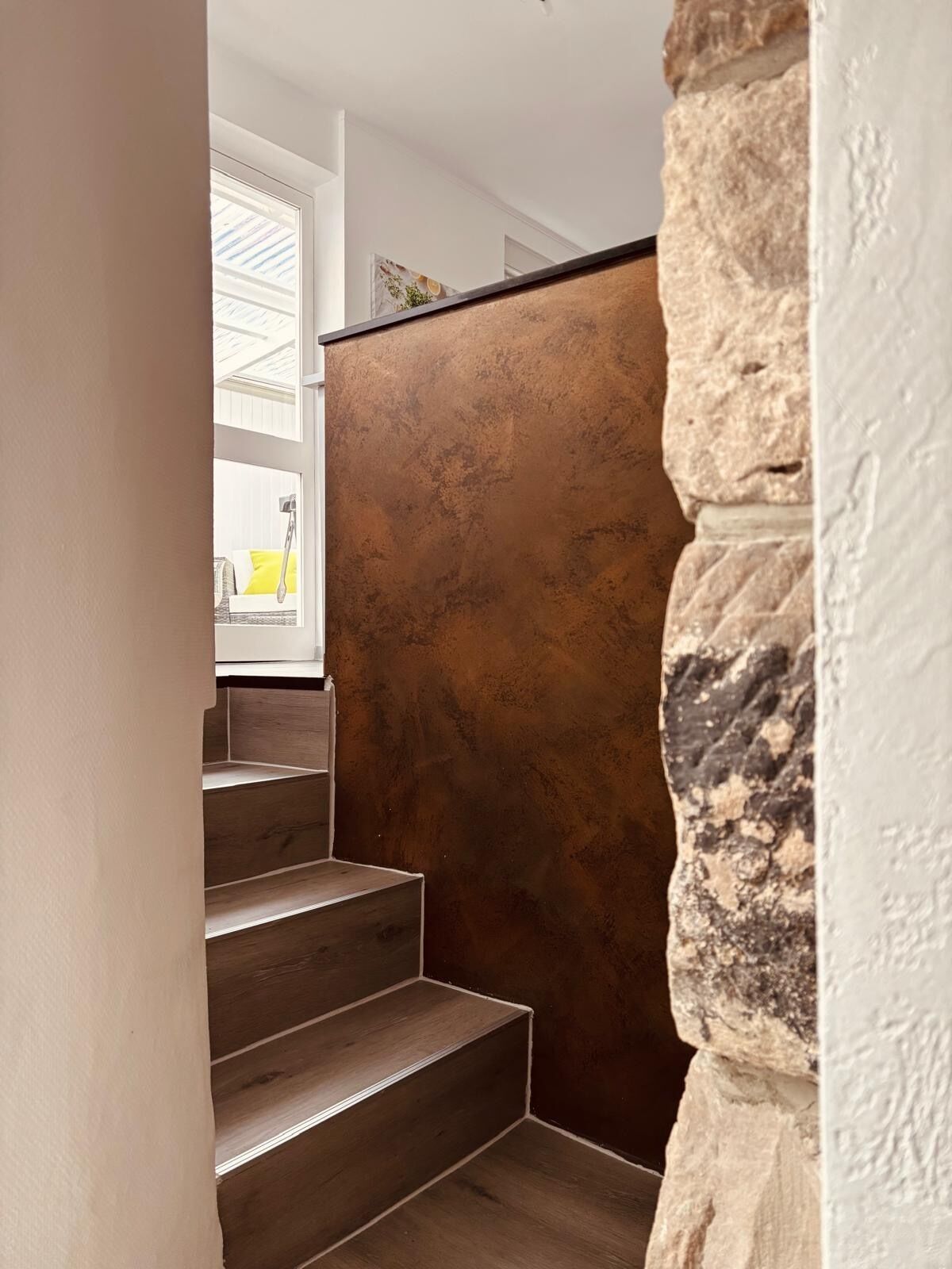 A staircase with wooden steps and a textured wall.