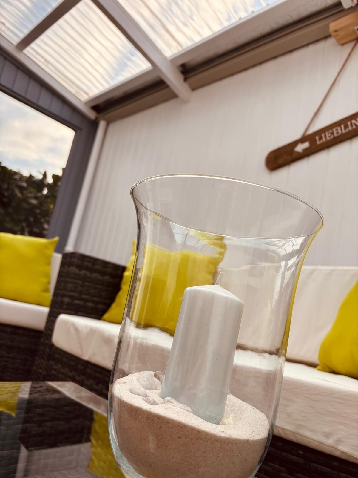 A clear glass vase with a white object inside, placed on a textured surface.