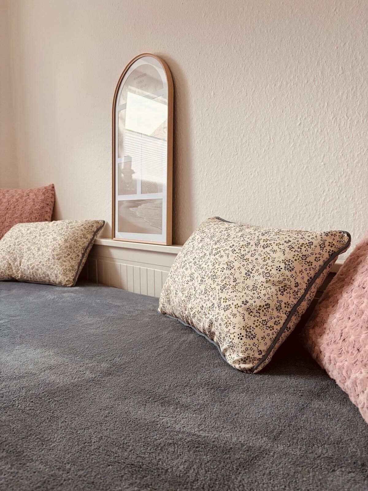 Une chambre à coucher avec un lit, deux oreillers, un miroir et un radiateur.