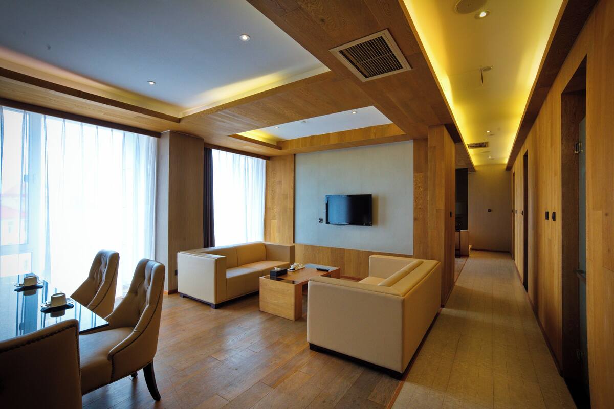 A modern living room with a sofa set, a coffee table, and a TV mounted on the wall.